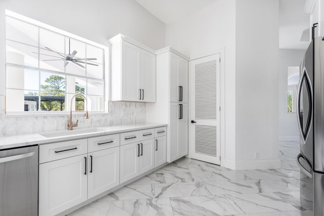 kitchen featuring backsplash, white cabinets, sink, ceiling fan, and stainless steel appliances