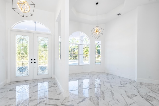 entryway with french doors, a tray ceiling, and a notable chandelier