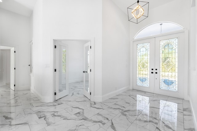 foyer with a chandelier, high vaulted ceiling, and french doors