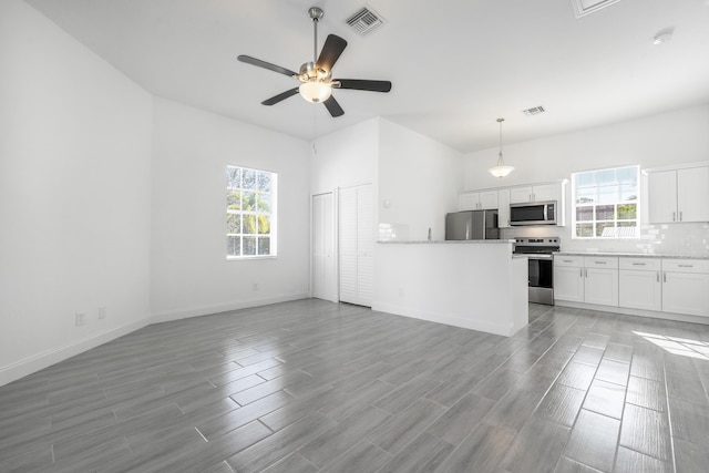 unfurnished living room featuring a wealth of natural light, ceiling fan, and wood-type flooring