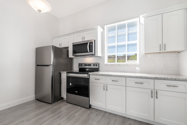 kitchen featuring appliances with stainless steel finishes, light hardwood / wood-style flooring, white cabinetry, and tasteful backsplash