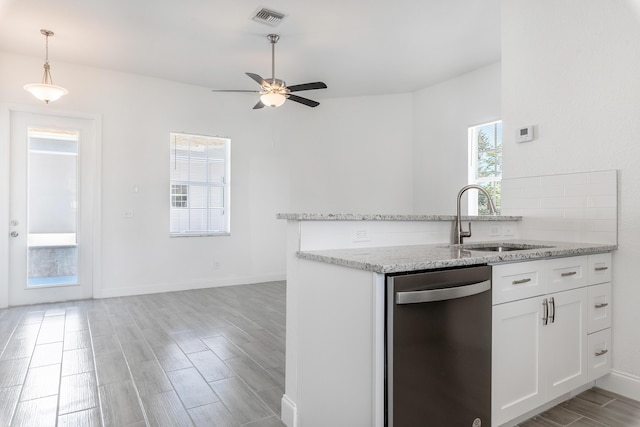 kitchen featuring light stone counters, white cabinetry, stainless steel dishwasher, and sink