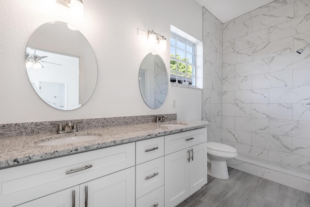 bathroom featuring ceiling fan, hardwood / wood-style floors, tiled shower, toilet, and vanity