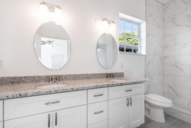 bathroom featuring ceiling fan, toilet, tiled shower, and vanity