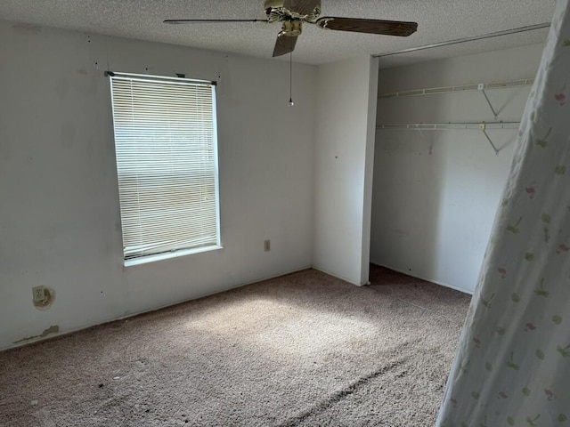 unfurnished bedroom with a textured ceiling, carpet floors, a closet, and a ceiling fan