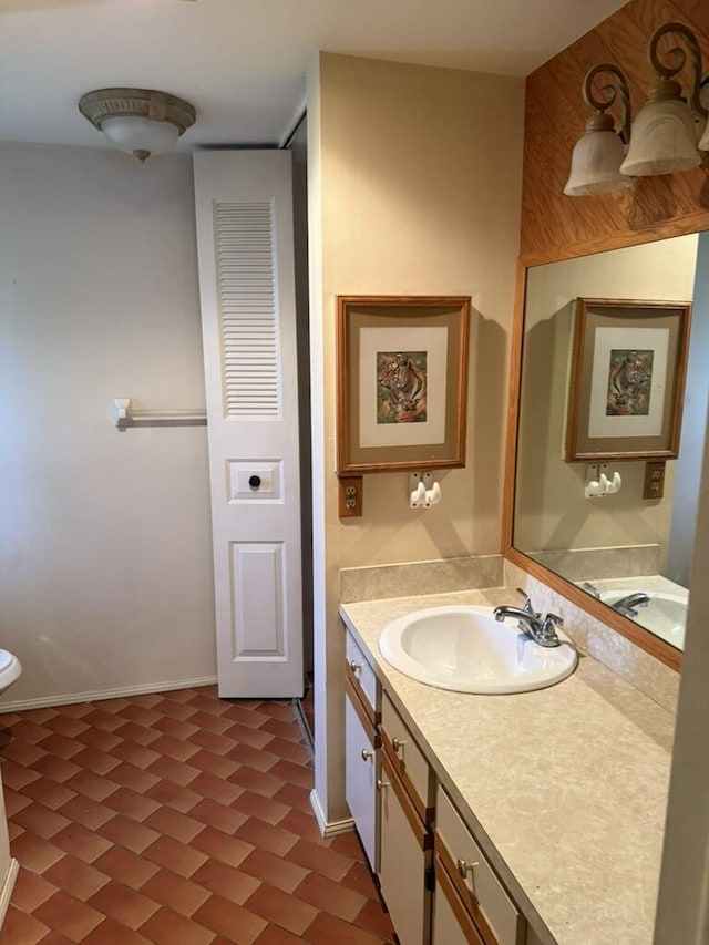 bathroom featuring toilet, vanity, and baseboards