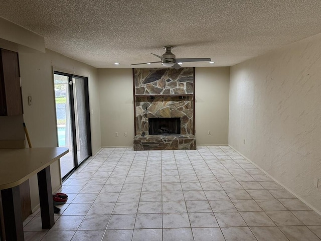 unfurnished living room featuring a textured wall, a textured ceiling, a ceiling fan, and a stone fireplace