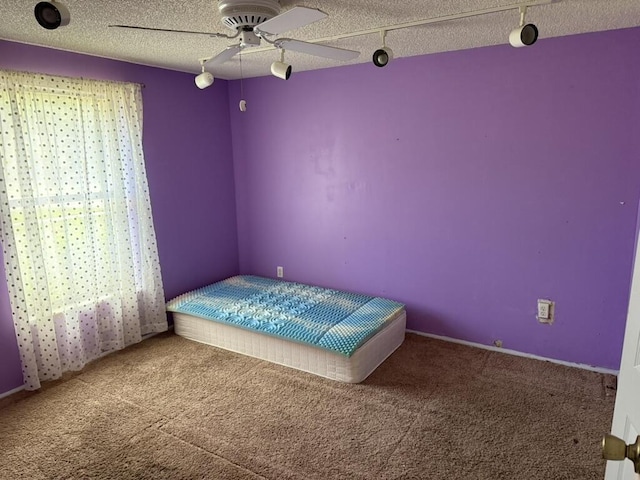 carpeted bedroom featuring a ceiling fan, a textured ceiling, and track lighting