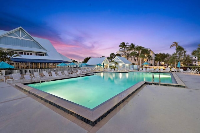 pool at dusk with a patio area