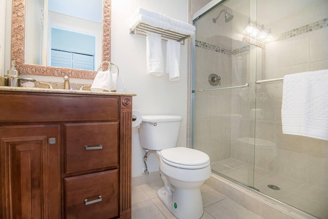 bathroom with tile patterned floors, a shower with door, vanity, and toilet