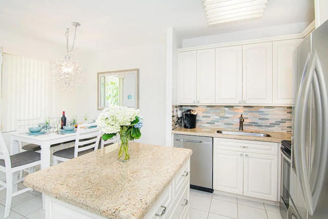 kitchen with backsplash, stainless steel appliances, a kitchen island, decorative light fixtures, and white cabinetry