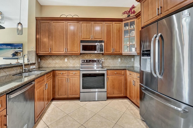 kitchen featuring appliances with stainless steel finishes, tasteful backsplash, dark stone countertops, and sink