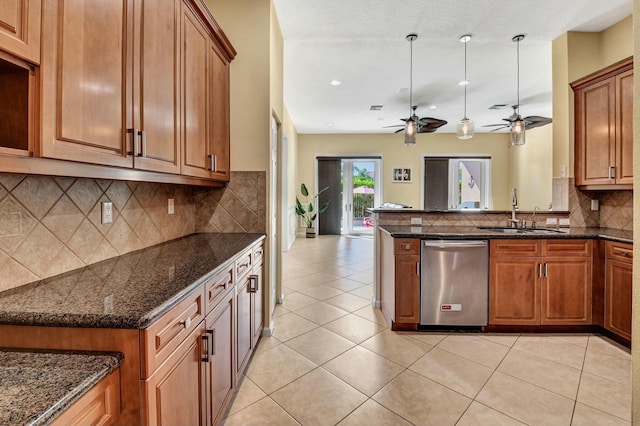 kitchen featuring light tile patterned flooring, stainless steel dishwasher, dark stone counters, and sink