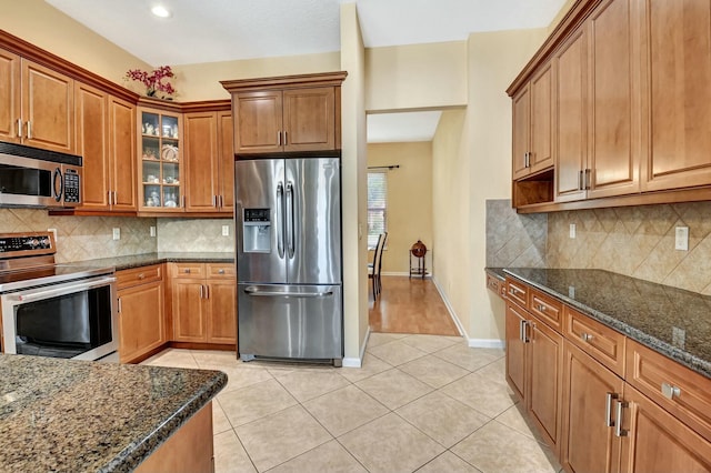 kitchen featuring tasteful backsplash, appliances with stainless steel finishes, and dark stone counters