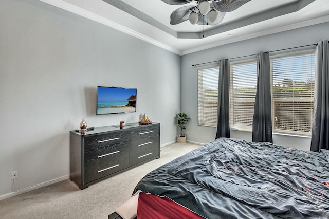 carpeted bedroom with a raised ceiling, ceiling fan, and ornamental molding