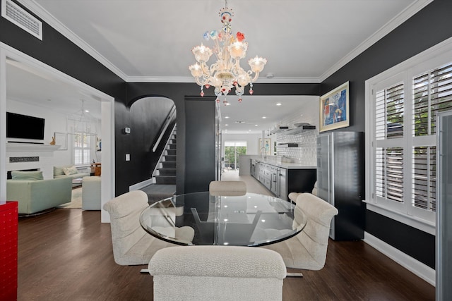 dining room featuring dark hardwood / wood-style flooring, an inviting chandelier, and ornamental molding