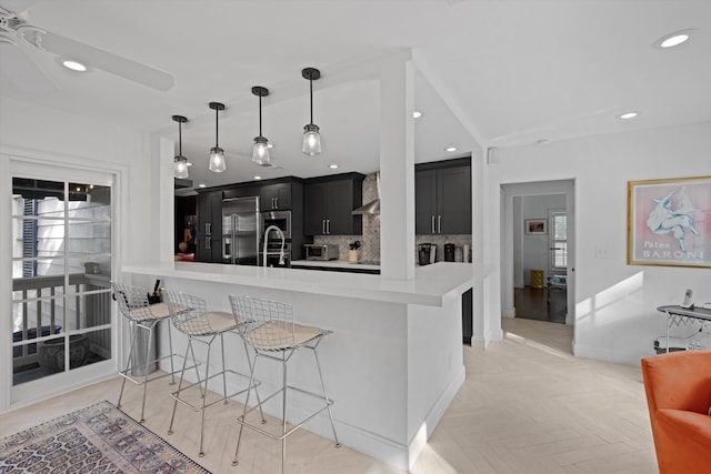 kitchen with a kitchen bar, appliances with stainless steel finishes, backsplash, kitchen peninsula, and wall chimney range hood