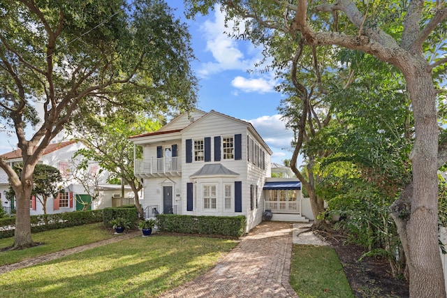 view of front of property featuring a balcony and a front lawn