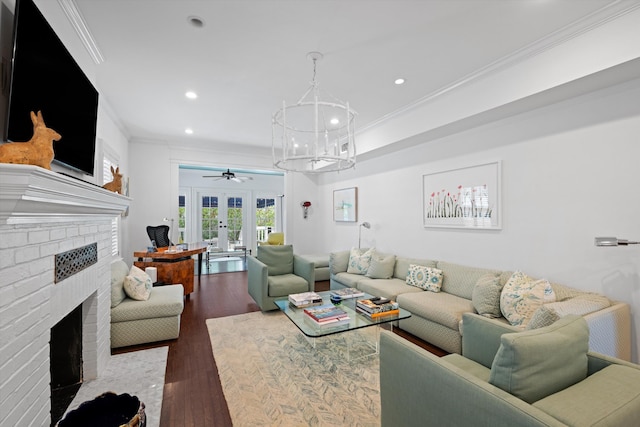 living room featuring french doors, a notable chandelier, crown molding, wood-type flooring, and a fireplace