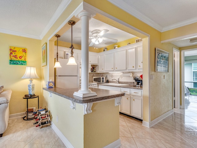 kitchen with kitchen peninsula, ornamental molding, white fridge, a kitchen bar, and white cabinetry