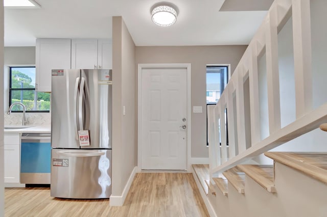 kitchen featuring white cabinets, appliances with stainless steel finishes, light wood-type flooring, and sink