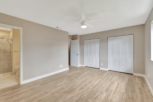 unfurnished bedroom featuring ceiling fan, light hardwood / wood-style floors, connected bathroom, and two closets