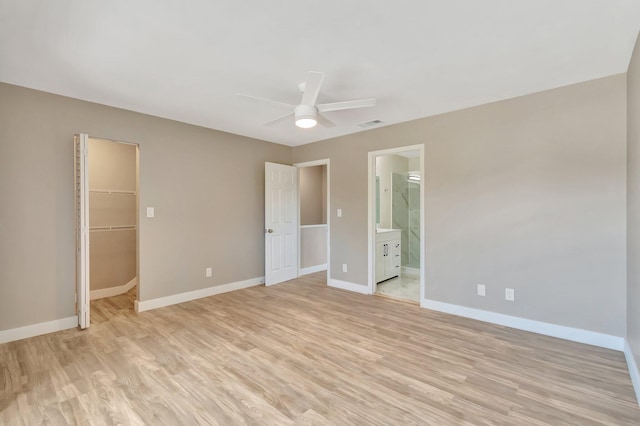 unfurnished bedroom with a spacious closet, ceiling fan, ensuite bathroom, light hardwood / wood-style floors, and a closet