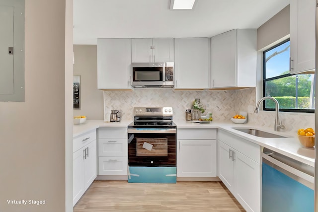 kitchen with electric panel, sink, light wood-type flooring, appliances with stainless steel finishes, and white cabinetry