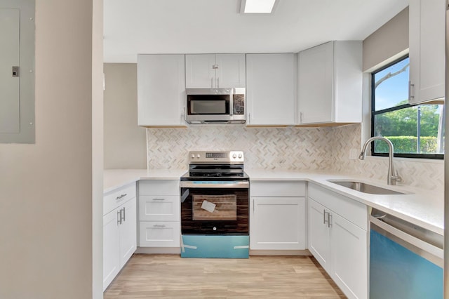 kitchen with appliances with stainless steel finishes, electric panel, white cabinetry, and sink