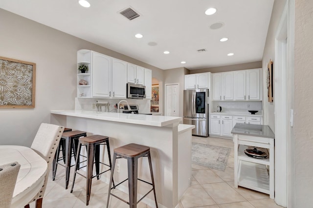 kitchen with kitchen peninsula, white cabinets, and stainless steel appliances