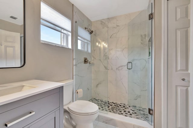 bathroom featuring a shower with door, vanity, and toilet