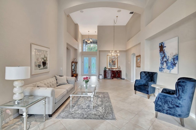 tiled living room featuring french doors, a towering ceiling, and an inviting chandelier