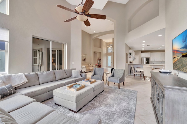 tiled living room with ceiling fan and a high ceiling