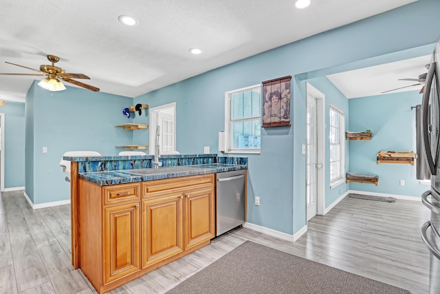 kitchen featuring kitchen peninsula, dishwasher, a textured ceiling, and light hardwood / wood-style flooring