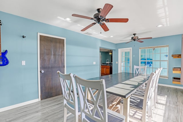 dining room featuring ceiling fan, sink, and light hardwood / wood-style flooring