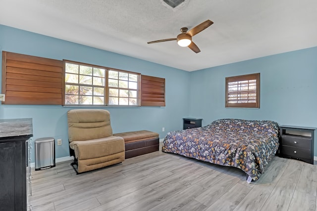 bedroom featuring ceiling fan, a textured ceiling, and light wood-type flooring