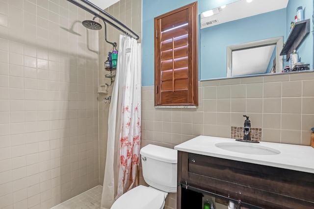 bathroom featuring walk in shower, vanity, toilet, and tile walls