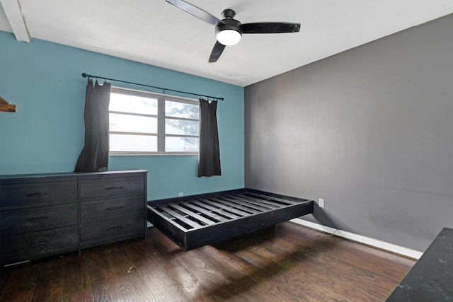 unfurnished bedroom with beamed ceiling, dark hardwood / wood-style flooring, and ceiling fan