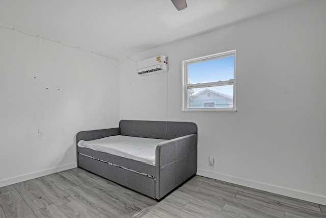 living area with ceiling fan, light hardwood / wood-style floors, and an AC wall unit