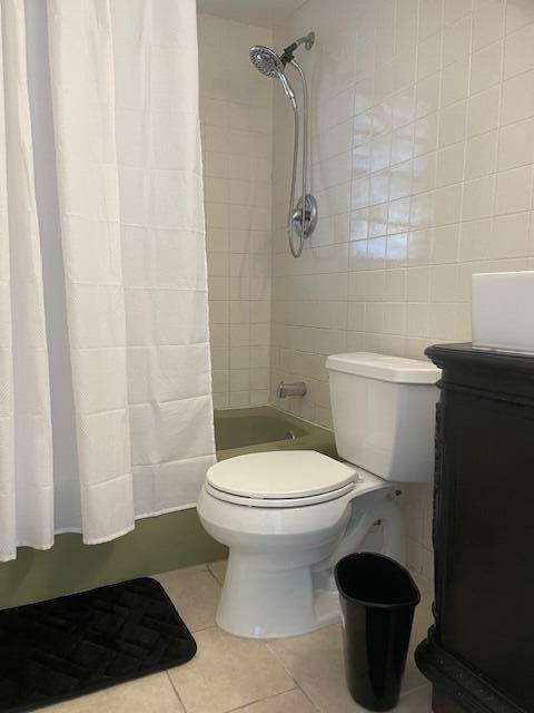 full bathroom with vanity, shower / tub combo with curtain, tile walls, tile patterned flooring, and toilet