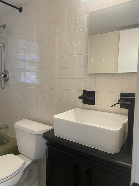 full bathroom featuring shower / bathtub combination, vanity, toilet, and tile walls