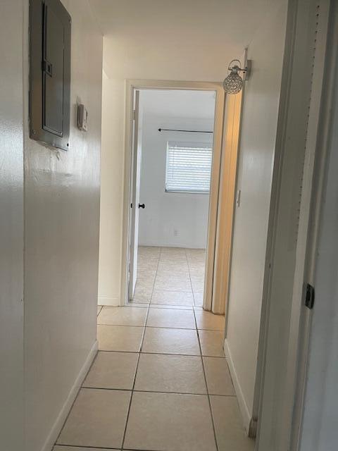 hall with light tile patterned floors and electric panel