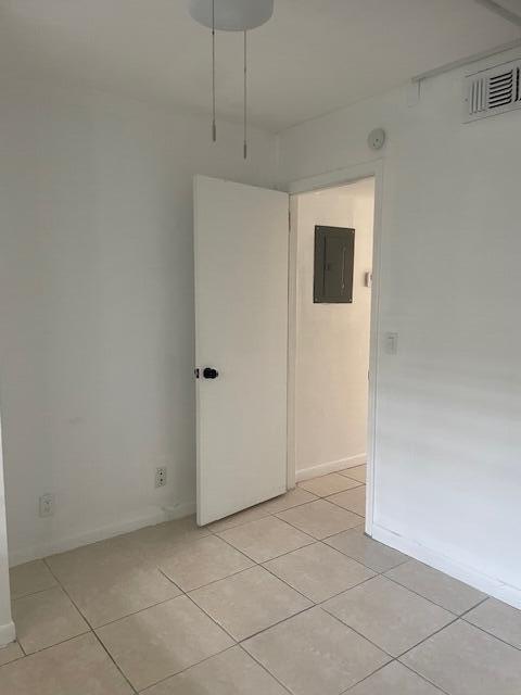 empty room with light tile patterned flooring and electric panel