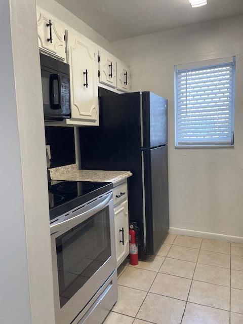 kitchen featuring electric range, white cabinetry, and light tile patterned flooring