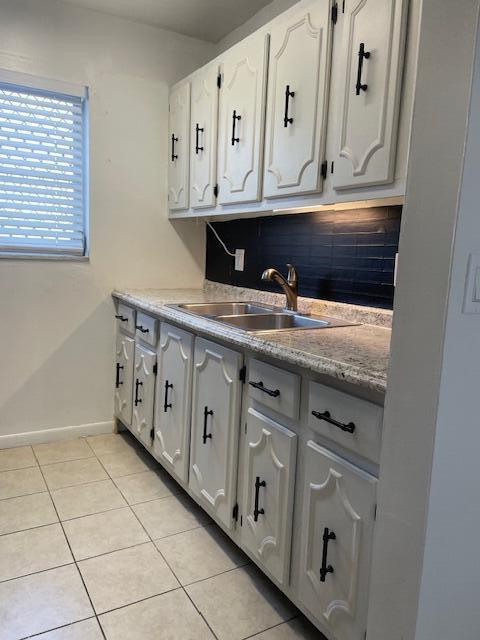 kitchen with sink, white cabinets, and light tile patterned flooring