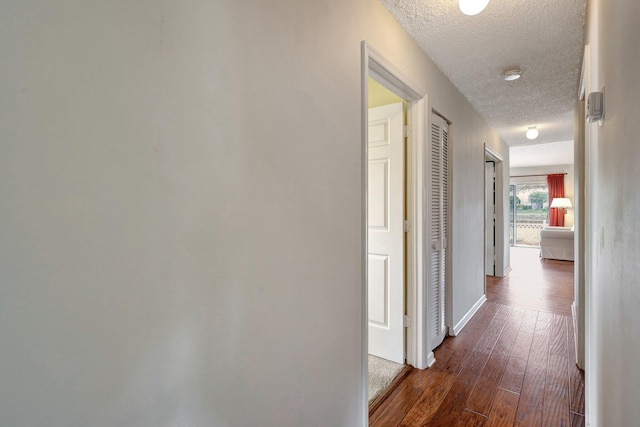 hall with dark hardwood / wood-style floors and a textured ceiling