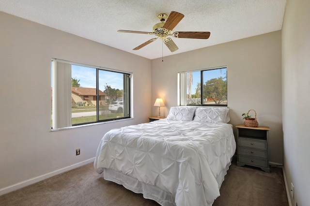 bedroom featuring multiple windows, a textured ceiling, ceiling fan, and dark colored carpet