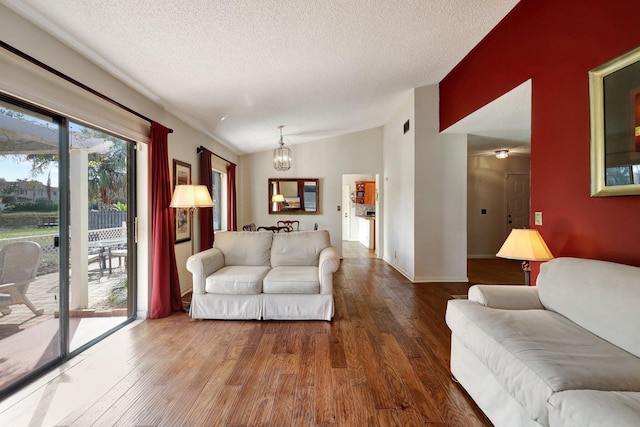 living room with hardwood / wood-style flooring, lofted ceiling, a notable chandelier, and a textured ceiling