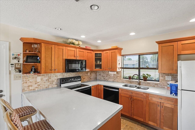 kitchen with a breakfast bar, sink, backsplash, black appliances, and a textured ceiling