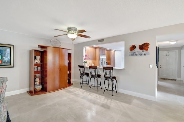 interior space with kitchen peninsula, stainless steel fridge with ice dispenser, a breakfast bar, and ceiling fan